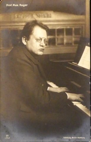 Reger, Max: - [Fotopostkarte, halbe Figur nach halbrechts, am Klavier]