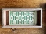  - Lotto-game, made in Germany/ Wooden box (11 x 22 x 5 cm) with lithographed illustration on the lid. Eleven cards (16 x 8 cm) thin cardboard with green numbers, and 86 wooden fiches with a number in. A few of the fiches have a letter in pen on the